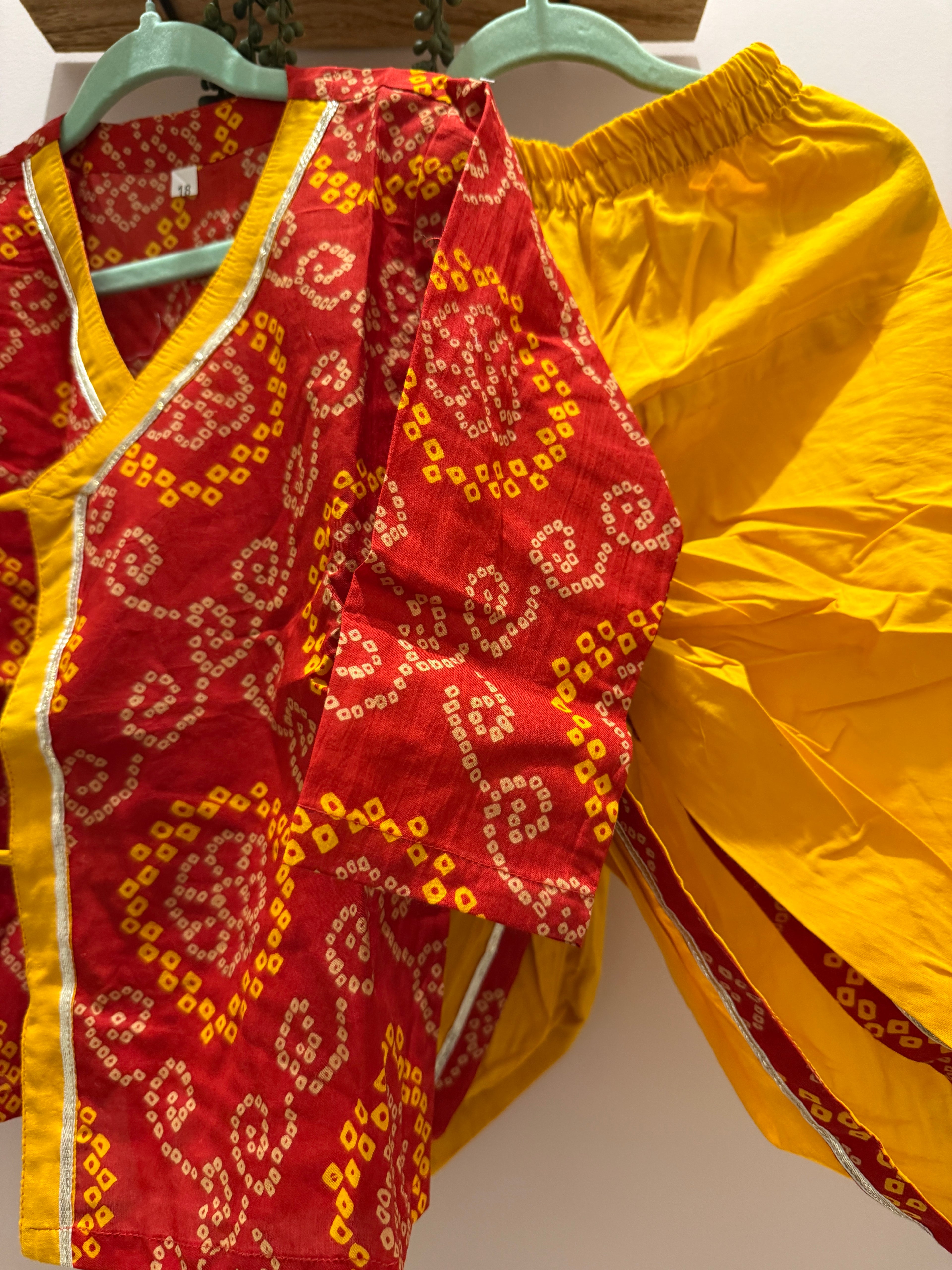 Close-up of red bandhani kurta with yellow border and yellow tie-up details for boys